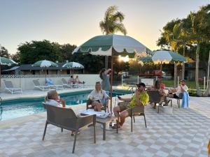 um grupo de pessoas sentadas em cadeiras à beira de uma piscina em The Timothée Resort em Busselton