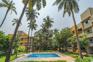 a pool in front of a building with palm trees at Earthlings : Anjuna beach- 2BHK with swimming pool in Anjuna