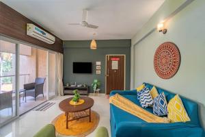 a living room with a blue couch and a table at Earthlings : Anjuna beach- 2BHK with swimming pool in Anjuna