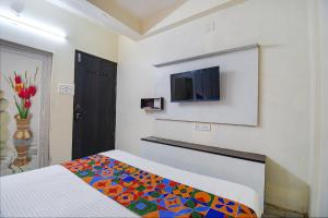 a bedroom with a bed and a tv on a wall at FabHotel Green Leaf I in Kolkata
