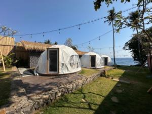 drie tenten op een stenen muur naast de oceaan bij Glamping @ Pebbles & Fins in Kubu