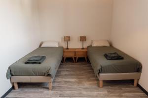 two twin beds in a room with two lamps at La ferme du 645 in Entraigues-sur-la-Sorgue