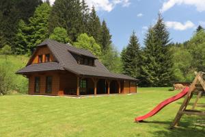 a log cabin with a red slide in a yard at Dřevěnice v Brodské in Nový Hrozenkov