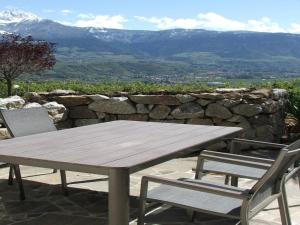a wooden picnic table and two chairs with a stone wall at Plarserhof in Lagundo