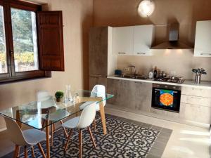 ヴィットーリアにあるVigna di pettineo - guest houseのキッチン(ガラスのテーブル、椅子、コンロ付)