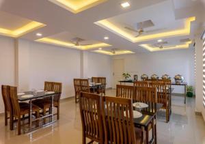 une salle à manger avec des tables et des chaises en bois dans l'établissement Airport Avenue Plaza Cochin Airport, à Nedumbassery