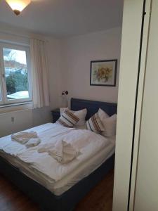 een slaapkamer met een bed met witte lakens en een raam bij Villa Sonneck App03 in Ostseebad Sellin