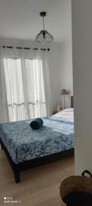een slaapkamer met een bed met blauwe lakens en witte gordijnen bij Confortable 2 pièces entre Menton et Monaco avec parking privé in Roquebrune-Cap-Martin