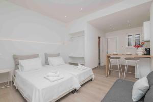 a white bedroom with a large bed and a kitchen at E&G Figareto apartments 10 in Kanoni