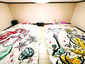 two beds with drawings of mermaids on their sheets at メゾンクレスタ in Tokyo