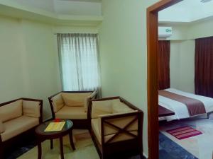 Cette chambre comprend un lit, un canapé et une chaise. dans l'établissement Hotel Suite Sadaf, à Kelātali
