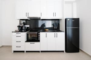 a kitchen with white cabinets and a black refrigerator at Ennea Suites-Luna suite in Flámbouras