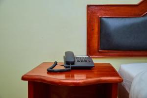 un teléfono sentado en una mesa junto a una cama en KILI CRANE LODGE ARUSHA, en Arusha