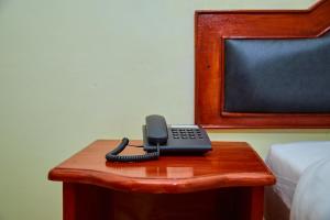 a phone sitting on a table next to a bed at KILI CRANE LODGE ARUSHA in Arusha