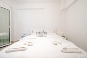 a white bedroom with a large white bed with towels on it at Ennea Suites-Luna suite in Flámbouras