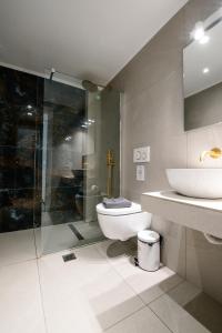 a bathroom with a toilet and a glass shower at Ennea Suites-Luna suite in Flámbouras