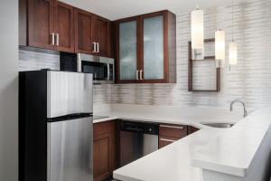 a kitchen with a refrigerator and a sink at Residence Inn by Marriott Fort Myers at I-75 and Gulf Coast Town Center in Estero