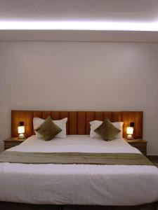شقق كالم الفندقية في الرياض: غرفة نوم بسرير ابيض كبير ومصباحين