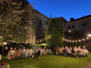 un groupe de personnes assises à des tables dans un jardin la nuit dans l'établissement AL TORRIONE, à Casalmaggiore