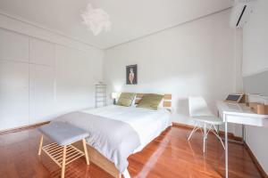 a white bedroom with a bed and a desk at Open -view Apartment, YGEIA Hospital in Athens
