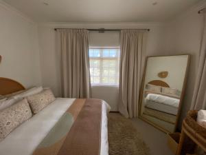 a bedroom with a bed and a mirror and a window at Barford Haven in Hermanus