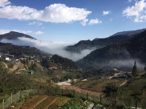 a view of a valley with clouds in the mountains at Scenic Views Farmstay And Hostel Sapa in Sa Pả