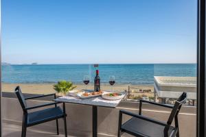 Horizon Beachfront Apartments في لاغاناس: طاولة مع كؤوس للنبيذ وصحن من الطعام على الشاطئ