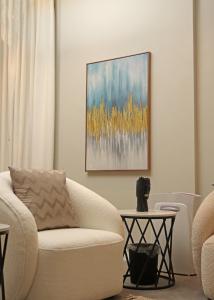 ein Wohnzimmer mit einem weißen Stuhl und einem Gemälde in der Unterkunft شقه باثاث مودرن تقع في برج سكني فاخر in Riad