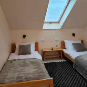 two beds in a room with a window at Chwilo Trwaj dom z jacuzzi, sauną i kominkiem z widokiem na góry Korbielów Pilsko in Korbielów