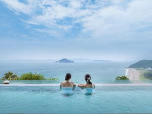 田原市Irago Ocean Resort的两个女人坐在一个无边游泳池里,望着大海