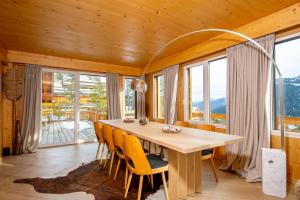 a dining room with a table and chairs and windows at Chalet Gemme - Magnifique chalet piscine sauna in Saint-Étienne-de-Tinée