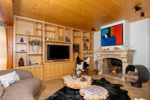 a living room with a fireplace and a tv at Chalet Gemme - Magnifique chalet piscine sauna in Saint-Étienne-de-Tinée