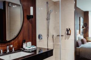 a bathroom with a shower and a sink and a mirror at AMERON Hamburg Hotel Speicherstadt in Hamburg
