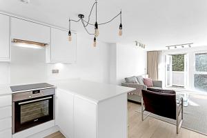 een keuken en een woonkamer met witte kasten en een open haard bij Belgravia Apartment 29 in Londen
