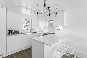 een witte keuken met witte kasten en een stoel bij Belgravia Apartment 29 in Londen