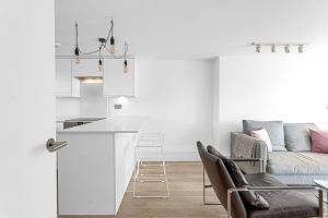 een witte keuken en een woonkamer met een bank bij Belgravia Apartment 29 in Londen