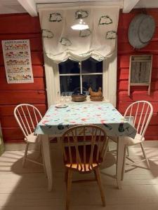 una mesa y sillas blancas en una habitación con ventana en Det røde huset på Vågnes, en Krokelvdalen
