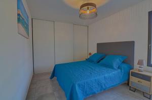 um quarto com uma cama azul e uma mesa de cabeceira em Appartement Le Frassu PORTICCIO em Porticcio