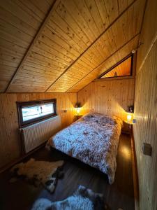 um quarto com uma cama num quarto de madeira em Căsuța din Stejari-Transalpina em Novaci-Străini