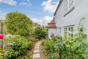 a garden in front of a white house at Hollyhedge Cottage in Briston