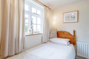una piccola camera con letto e finestra di Hollyhedge Cottage a Briston
