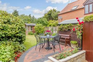 een patio met een tafel en stoelen in de achtertuin bij Hollyhedge Cottage in Briston