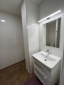 La salle de bains blanche est pourvue d'un lavabo et d'un miroir. dans l'établissement Kaštanová 27, à Olomouc