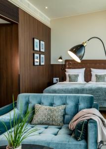 a bedroom with a blue couch and a bed at AMERON Hamburg Hotel Speicherstadt in Hamburg