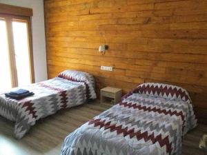 a bedroom with two beds and a wooden wall at Casa Rural La Malena in Azuara