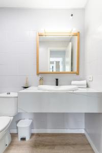 uma casa de banho branca com um lavatório e um espelho em Home2Book Stylish Apt Terrace & BBQ, Maspalomas em Maspalomas