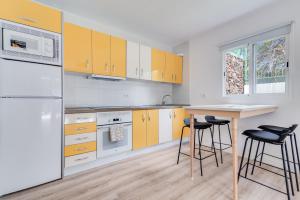 uma cozinha com armários amarelos, uma mesa e bancos em Home2Book Stylish Apt Terrace & BBQ, Maspalomas em Maspalomas
