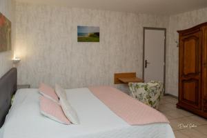 Schlafzimmer mit einem Bett mit rosa und weißen Kissen in der Unterkunft Chambres d'Ault in Ault