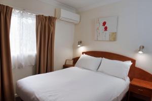um quarto com uma cama branca e uma janela em The Metropole Guest House Katoomba em Katoomba