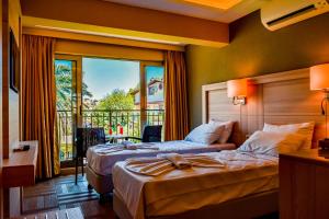 two beds in a hotel room with a balcony at TURUNÇ BAY CONTİ BOUTIQUE HOTEL in Marmaris